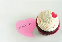 Cupcake with a heart shaped paper that reads thank you beside it