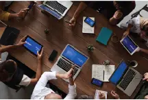 People with laptops sitting at board room table