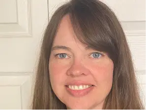 An image of Andrea Lorette smiling, standing in front of a white door.