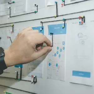 Person pinning paper on a white board