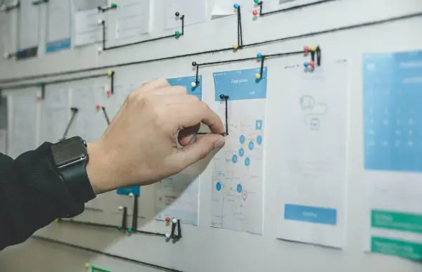 Person pinning paper on a white board