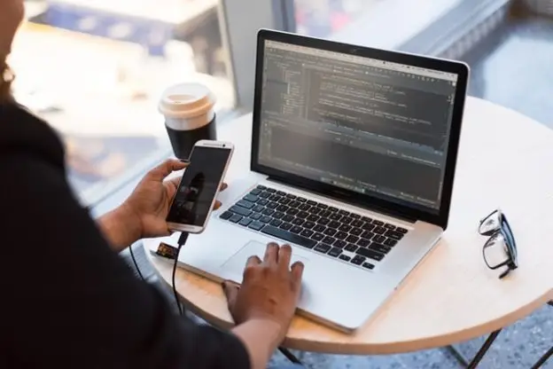 Women using a program through her phone connected to a laptop