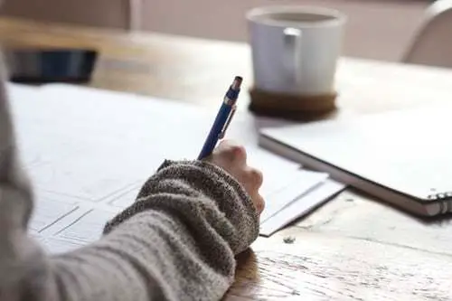 Hand holding a pen writing in a notebook