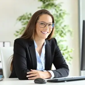 Woman sitting at a desk smiling while looking at the camera