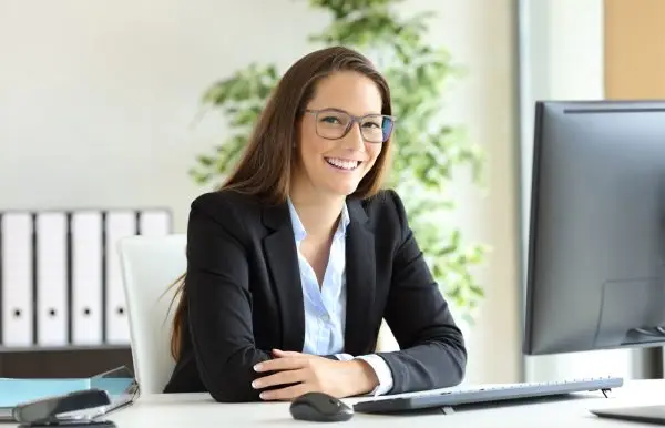 Woman sitting at a desk smiling while looking at the camera