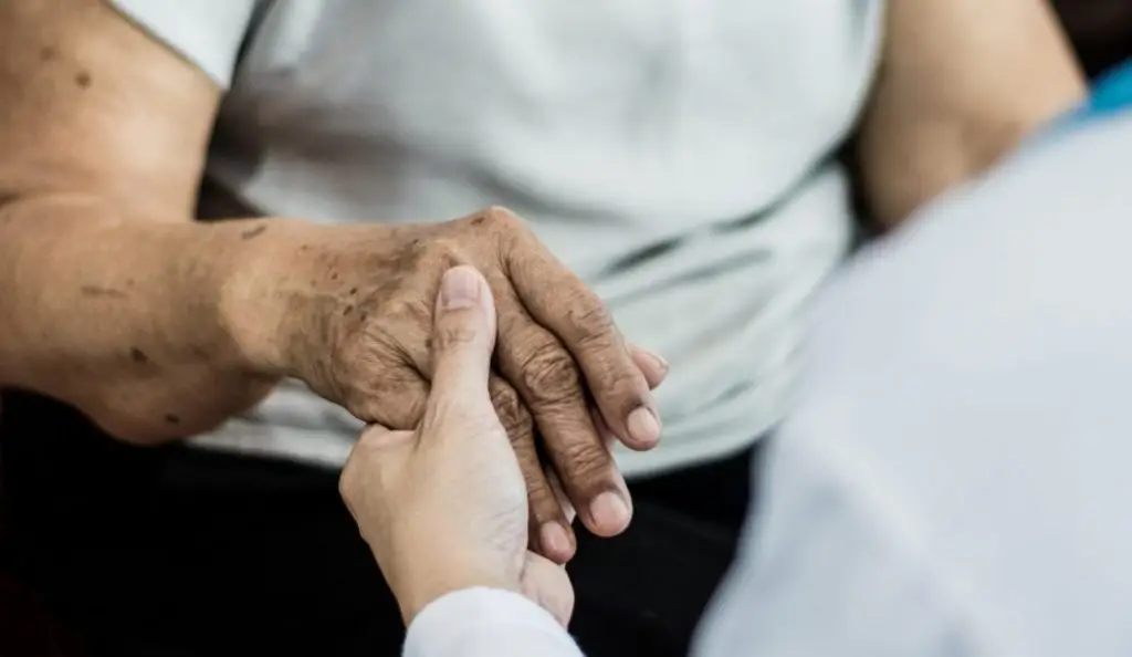 female senior elderly patient with caregiver in hospice care. Doctor hand with stethoscope check up older woman people. Old aging person seeing medical physician in hospital.