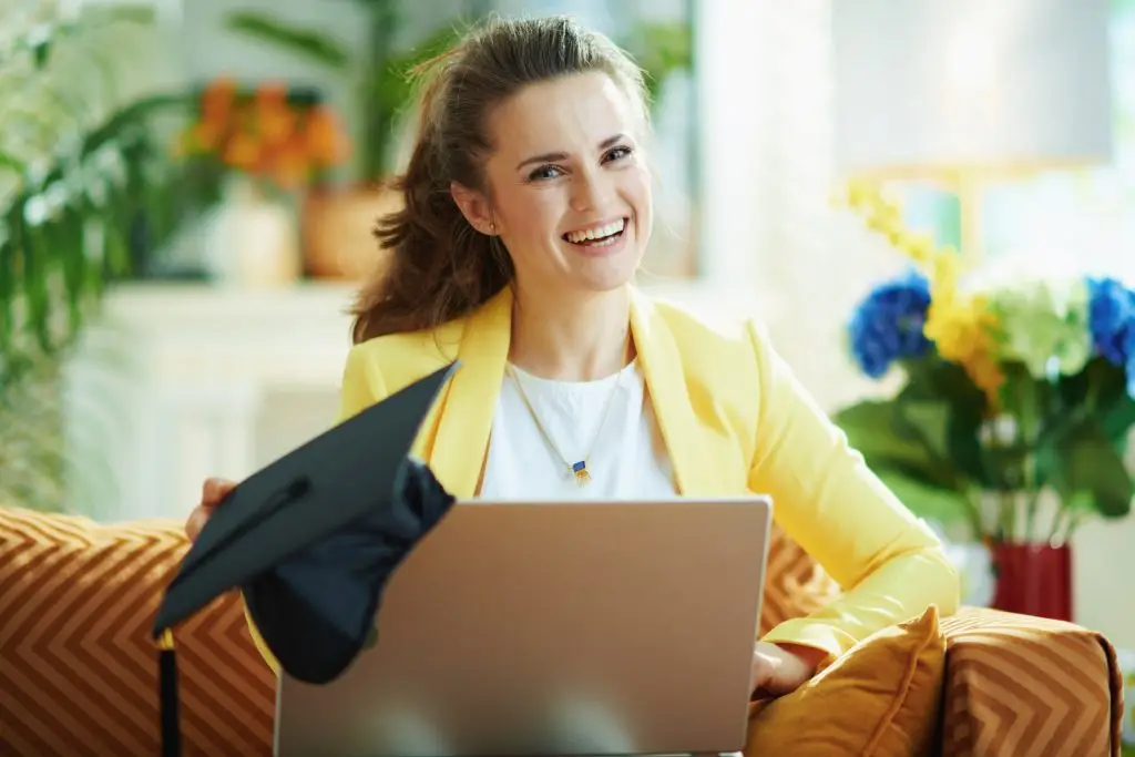 happy young woman with graduation cap and laptop