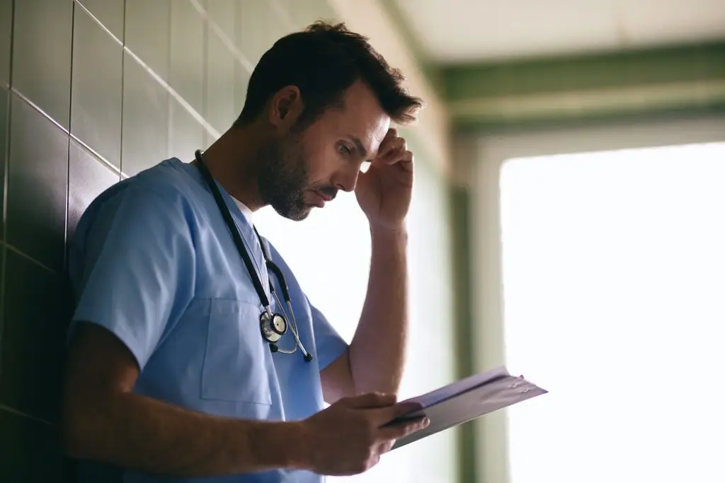 Stressed doctor reading medical documentation