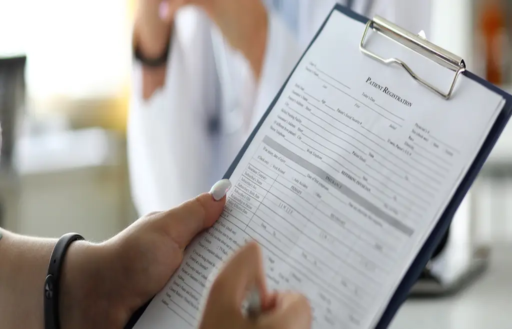 Female visitor filling out medicine documents in doctor office close-up